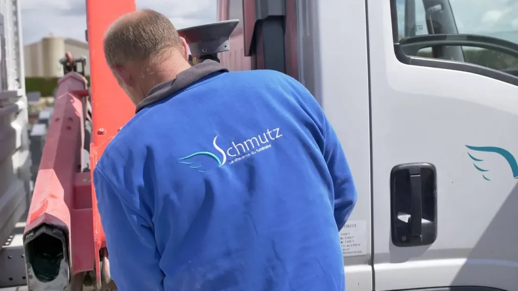 Marbreur en tenue professionnelle Schmutz près du camion de l'entreprise funéraire.