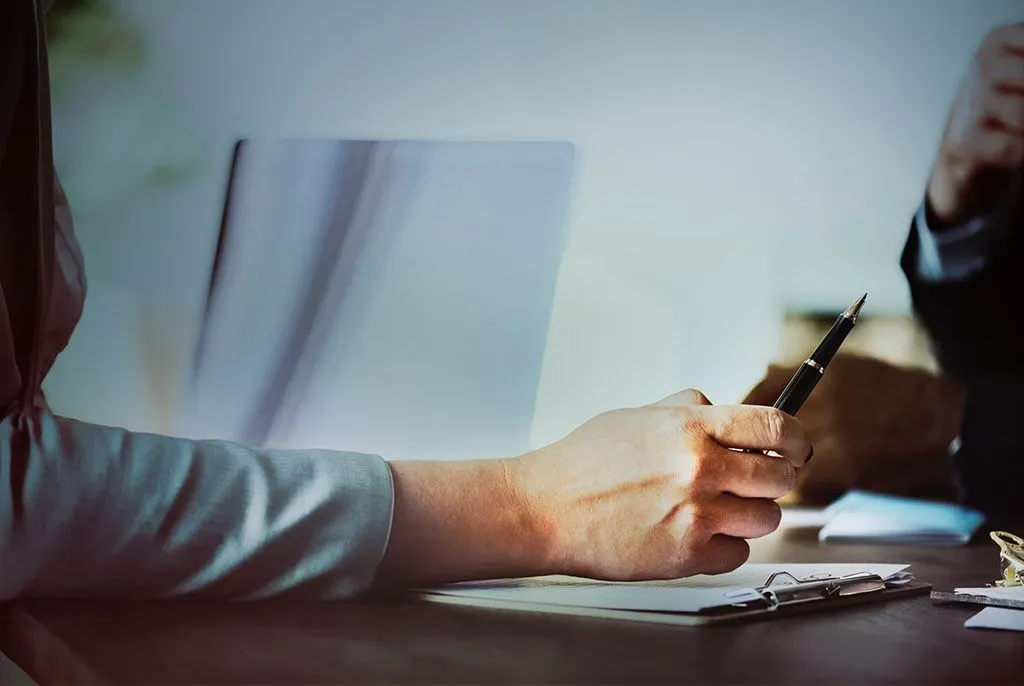 Main tenant un stylo pour signer un contrat de prévoyance obsèques.