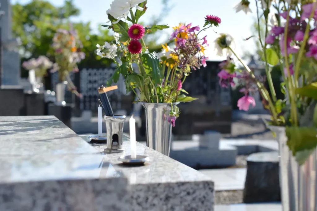 Vases de fleurs colorées et bougies sur une sépulture en marbre au cimetière