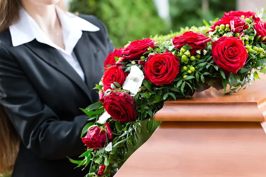 Roses rouges sur un cercueil en bois lors d'une cérémonie funéraire.
