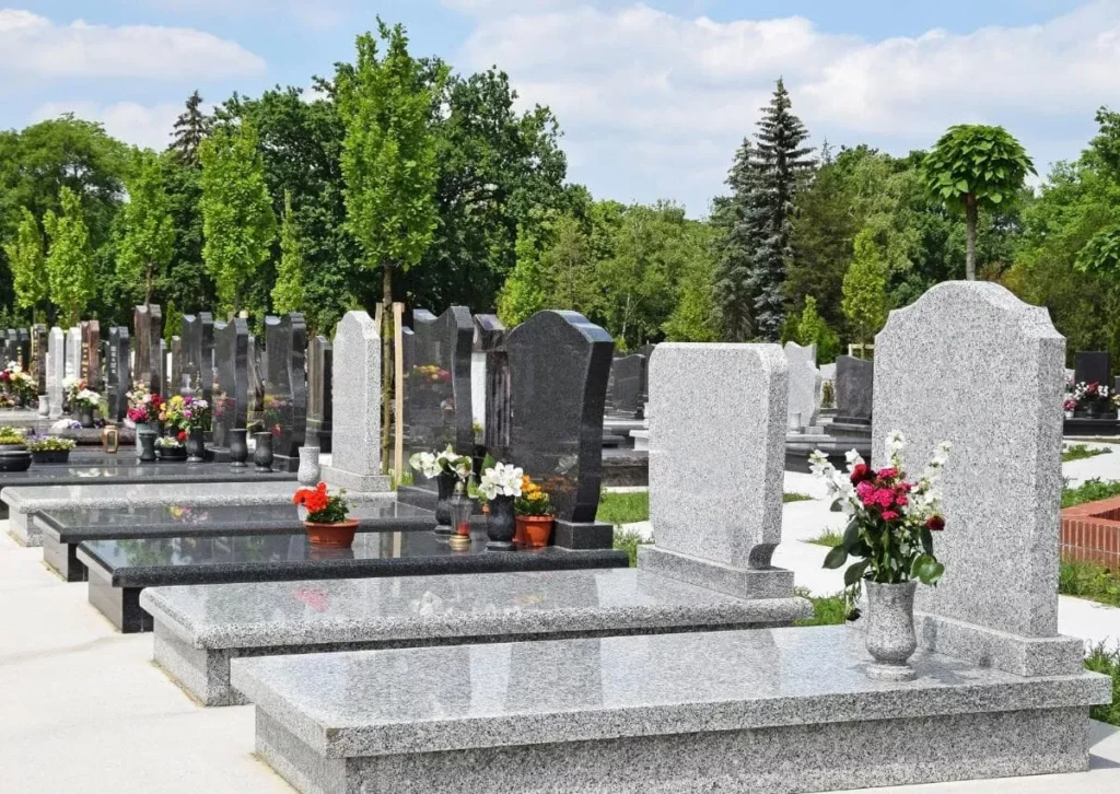 Allée de monuments funéraires en granit et bouquets de fleurs au cimetière